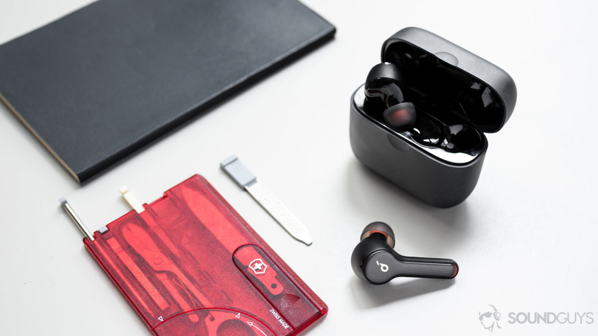 A picture of the Anker SoundCore Liberty Air 2 true wireless earbuds with one earbud in the charging case and another outside of it next to a multitool card.