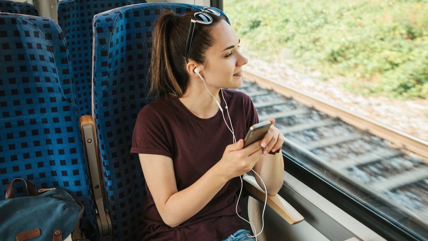 Young woman listens to music on the train