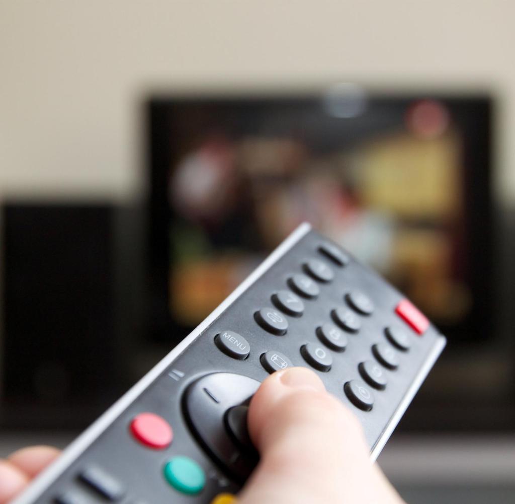 Human hand holding remote control change channels with TV.  Getty ImagesGetty Images