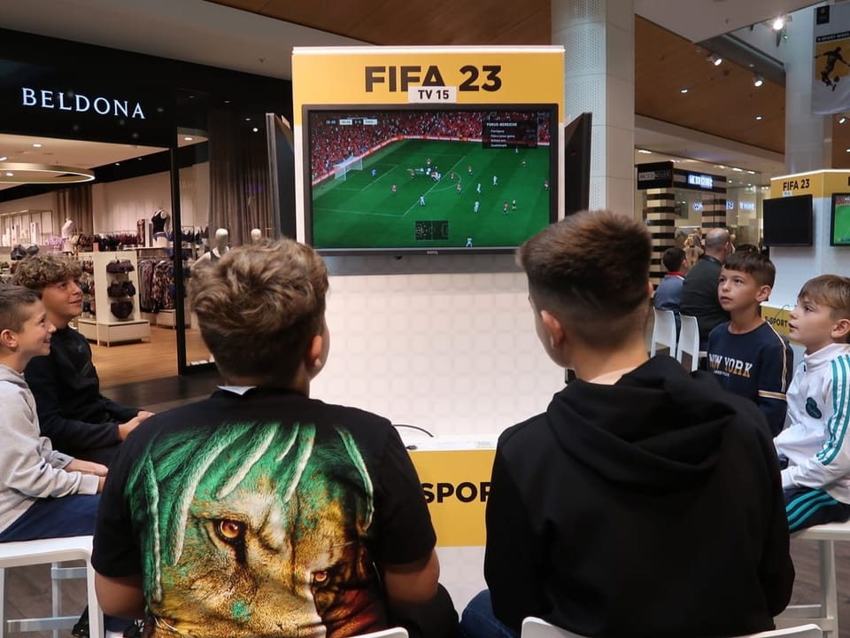 Young gamers play FIFA in a shopping mall.