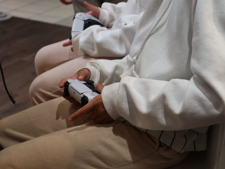 Two girls have game consoles in their hands.